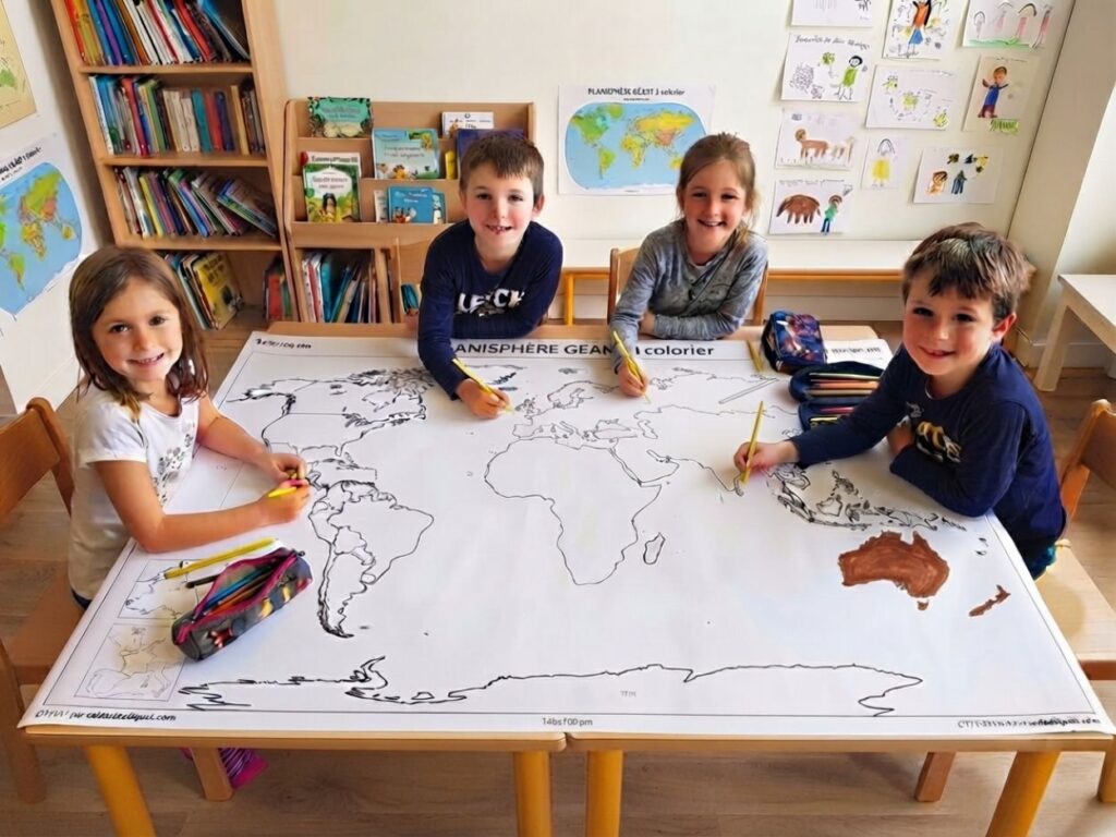 Quatre enfants souriants assis autour d'une grande table en train de colorier un planisphère géant.