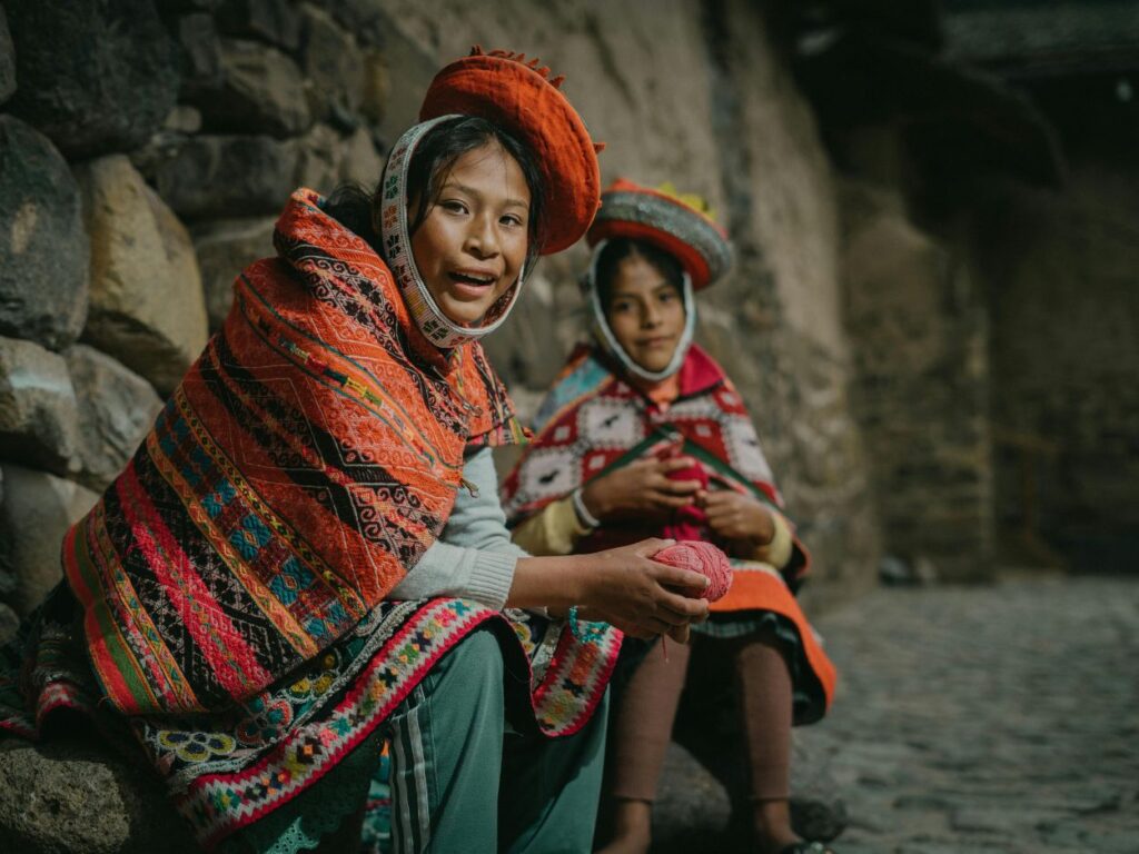 Deux jeunes filles en tenue traditionnelle péruvienne tenant de la laine.