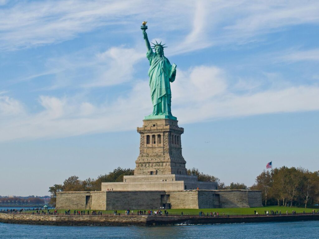Vue complète de la Statue de la Liberté sur son piédestal sous un ciel bleu dégagé.