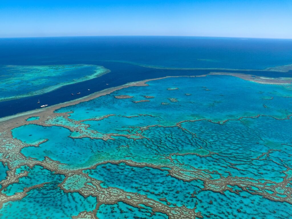 Vue aérienne spectaculaire de la Grande Barrière de Corail avec ses nuances de bleu turquoise et bleu profond.